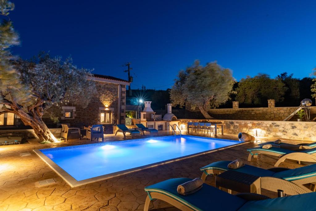 Una piscina de noche con sillas alrededor. en Villa Roi, en Kalathos