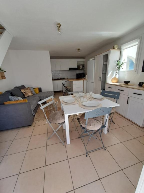 une table blanche et des chaises dans un salon dans l'établissement Maison en bord de mer, à Valras-Plage