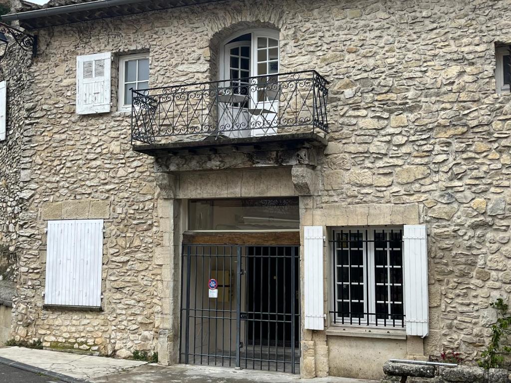 a stone building with a balcony and a door at Sur le Pont in Vaison-la-Romaine