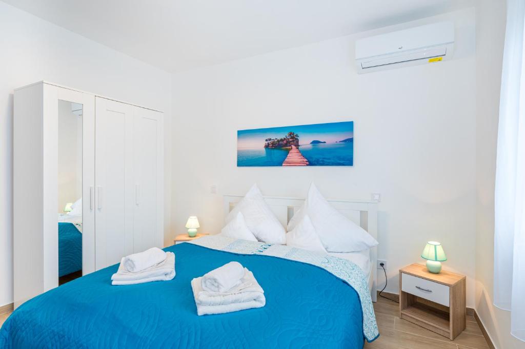 a bedroom with a blue bed with towels on it at Eternity Apartmanház in Keszthely