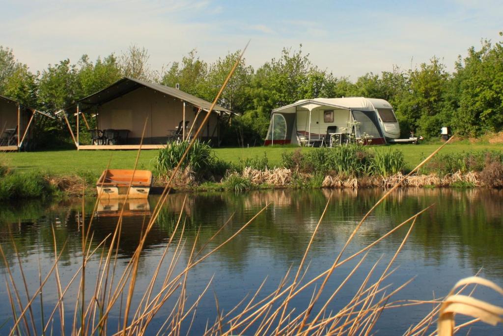 a camping site with a tent and a lake at Caravan met wijds uitzicht in Kuinre