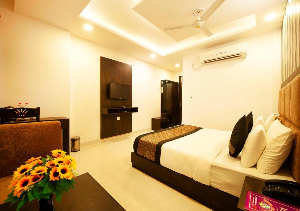Balwood Suites Near Delhi Airport في نيودلهي: غرفة في الفندق بها سرير وطاولة بها زهور