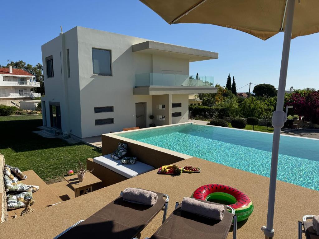 a swimming pool with chairs and an umbrella next to a house at Home21 in Asgourou