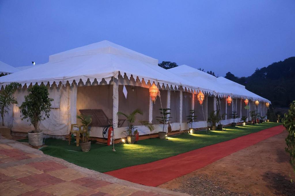 una grande tenda bianca con luci su un prato di Shivadya Camps MAHAKUMBH Mela a Allahābād