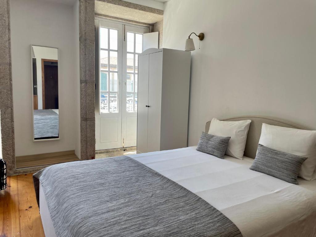 um quarto branco com uma cama grande e 2 almofadas em Douro River Cozy Flats no Porto