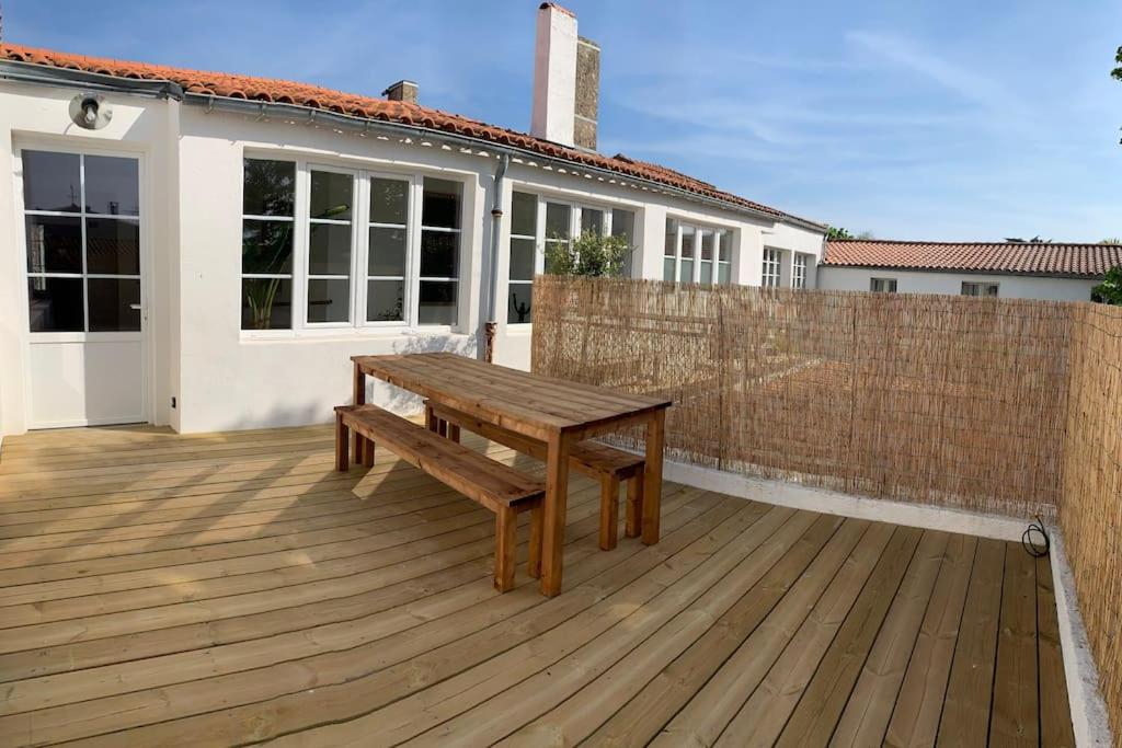 eine Holzterrasse mit einer Bank auf einem Haus in der Unterkunft Maison de ville avec terrasse in Saint-Denis-dʼOléron