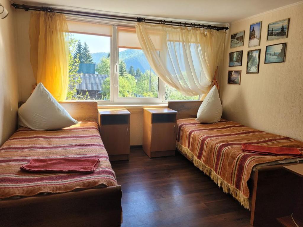 two beds in a room with a window at Карпатська Мавка in Vorokhta