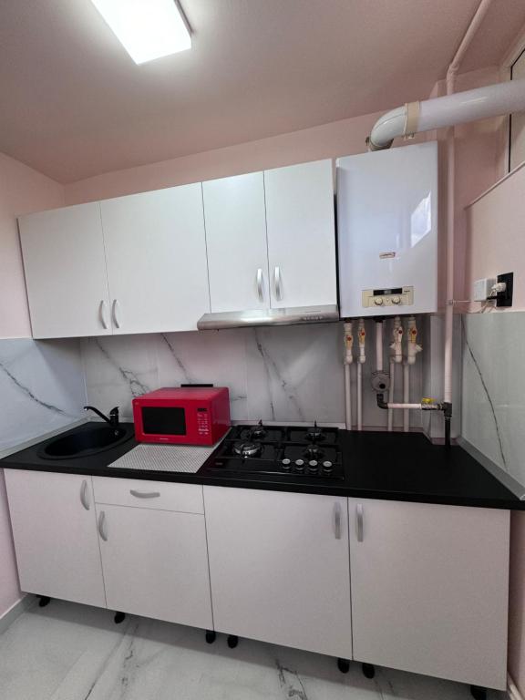 a kitchen with white cabinets and a red microwave at Studio Luigy in Turda