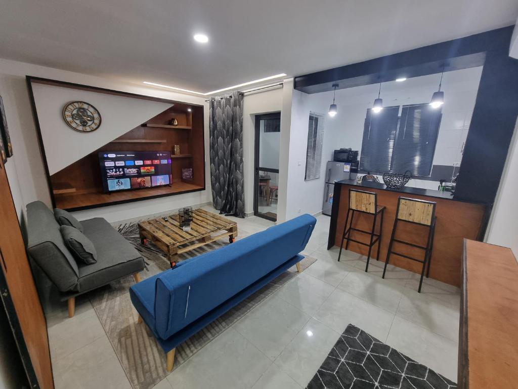 a living room with a blue couch and a kitchen at Appartements MAXIMA in Libreville