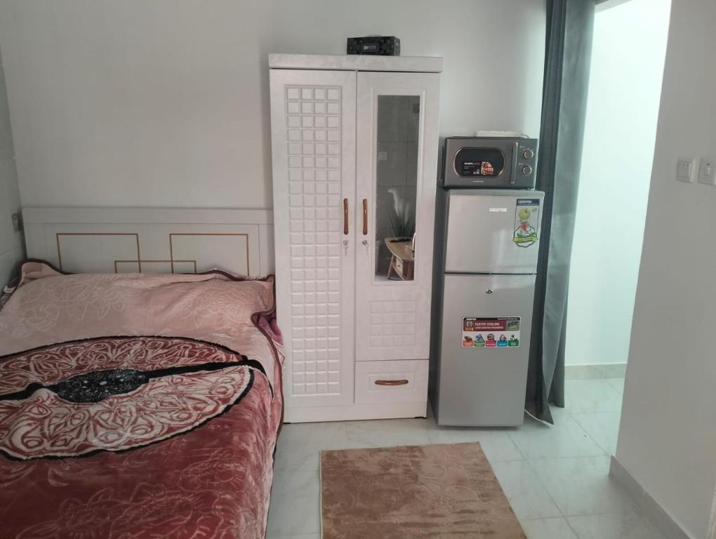 Schlafzimmer mit einem Bett neben einem Kühlschrank in der Unterkunft Luxor's Studio in Abu Dhabi