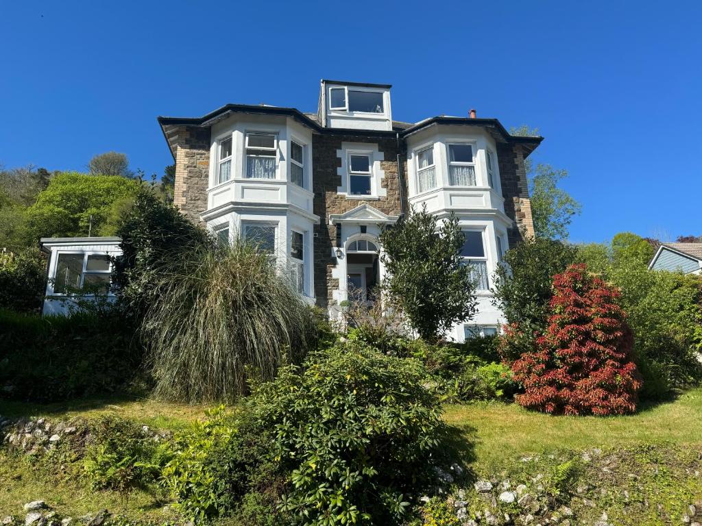 a large white house on a hill with bushes at Cairn House in Ilfracombe