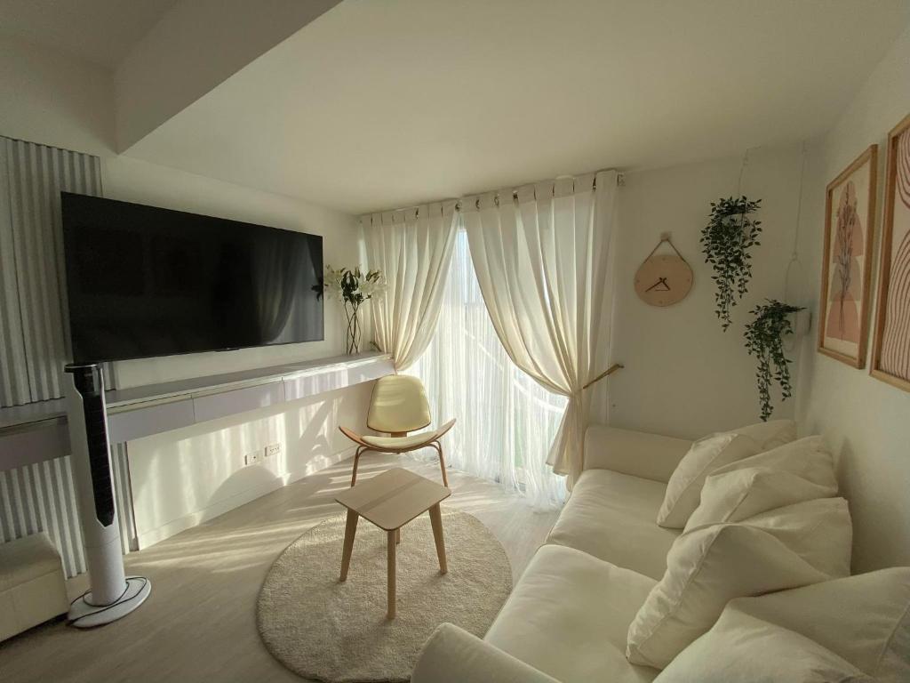 Il comprend un salon doté d'un canapé blanc et d'une télévision à écran plat. dans l'établissement Muji Inspired Beach view, à San Fernando