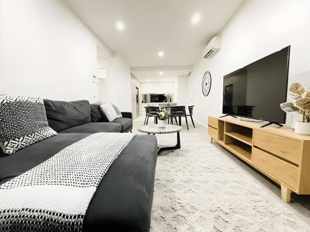 een woonkamer met een bank en een flatscreen-tv bij Mega Style Apartments Kings Domain in Melbourne