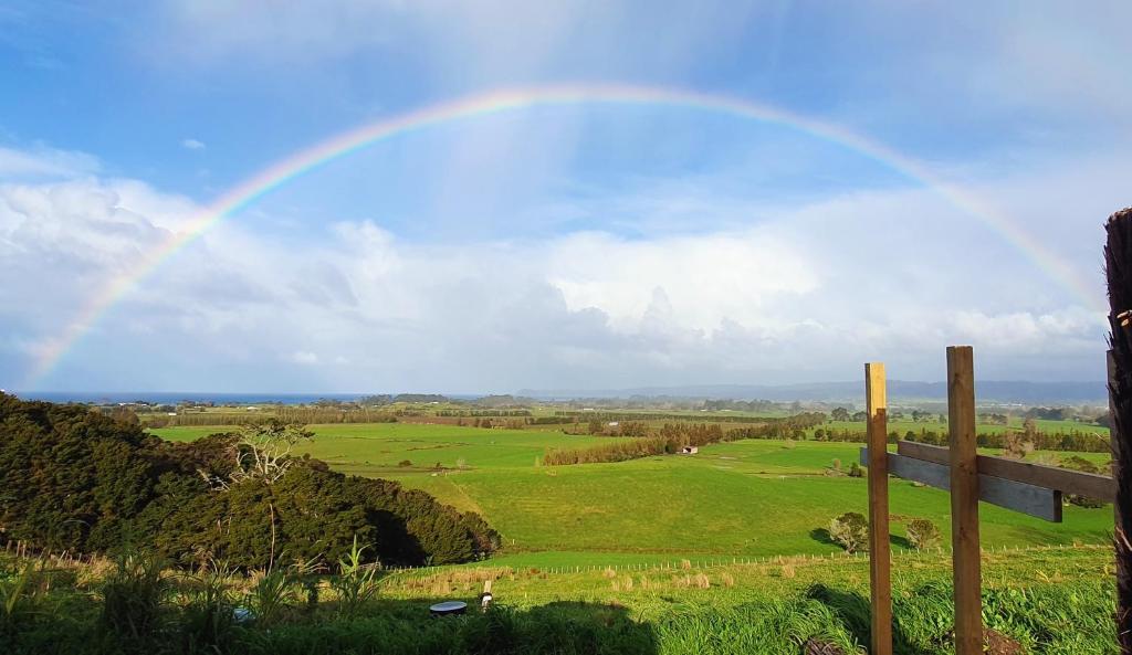 a rainbow in the sky over a green field at Waipu Off-grid Eco Geodesic Glamping Dome in Waipu