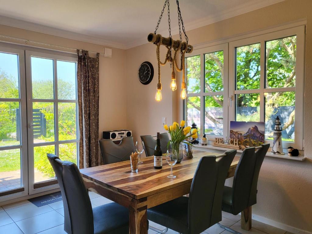 uma sala de jantar com uma mesa e cadeiras de madeira e janelas em Ferienhaus DHH "Unsere zweite Heimat" links em Sankt Peter-Ording