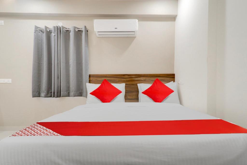a bedroom with a white bed with red pillows at Super OYO Flagship Prime Time Hotel in Kukatpalli