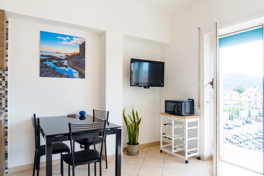 una sala da pranzo con tavolo, sedie e TV di Appartamento Il Mare e Dintorni a Portoferraio