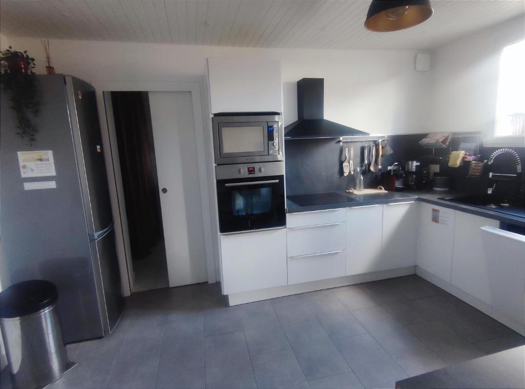 uma cozinha com armários brancos e um frigorífico de aço inoxidável em Agréable Maison, toute équipée, proche du lac d'Arjuzanx em Morcenx
