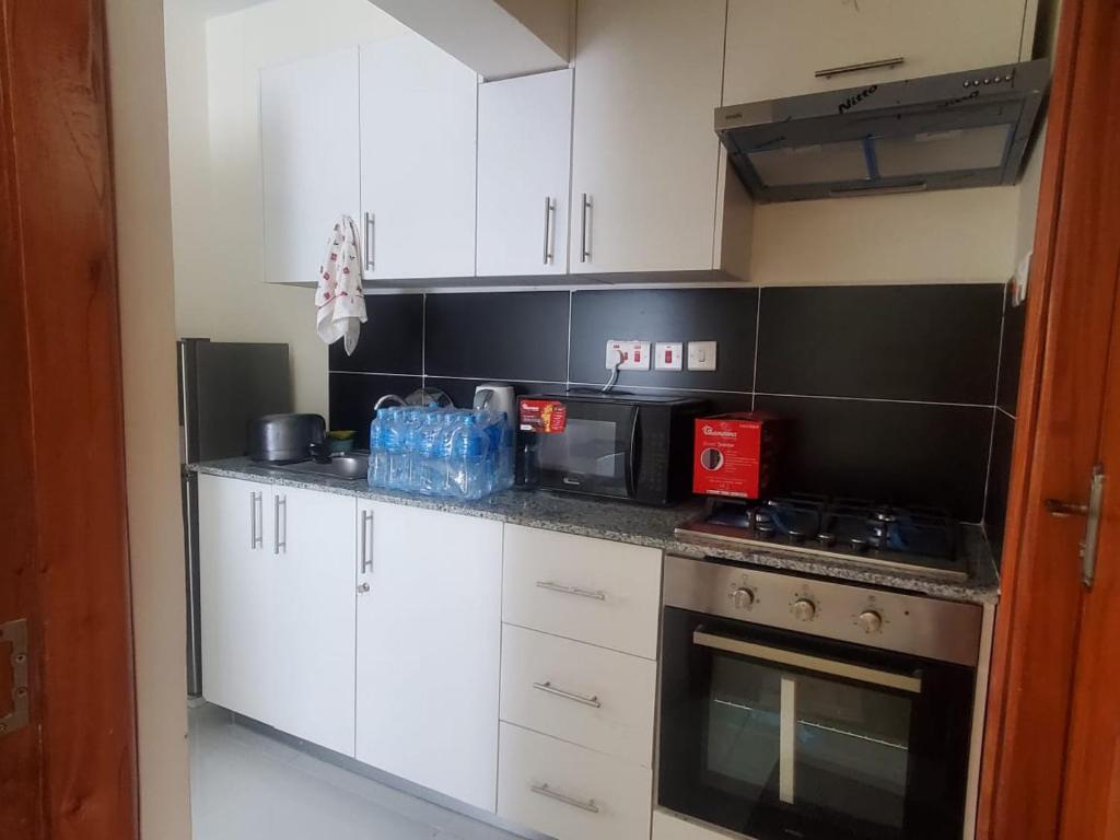 uma cozinha com armários brancos e um forno com placa de fogão em Rozina Apartments em Nairobi