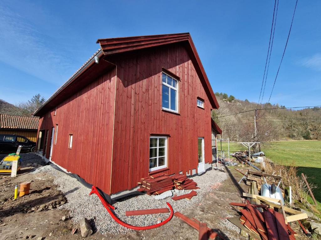 eine rote Scheune, in der ein Gebäude gebaut wird in der Unterkunft Country apartment by the sea in Gare