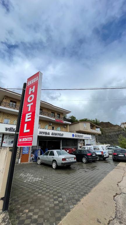 a parking lot with cars parked in front of a building at Hotel Skura in Librazhd
