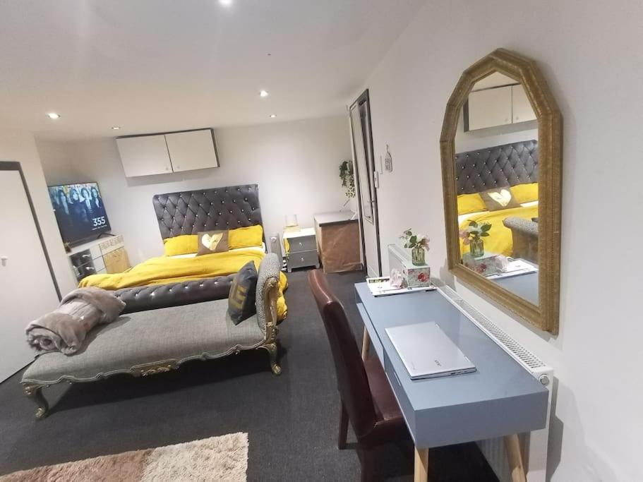 a bedroom with a bed and a table and a mirror at A Cosy Deluxe Size Studio With Queen size and Sofa Bed in Leeds