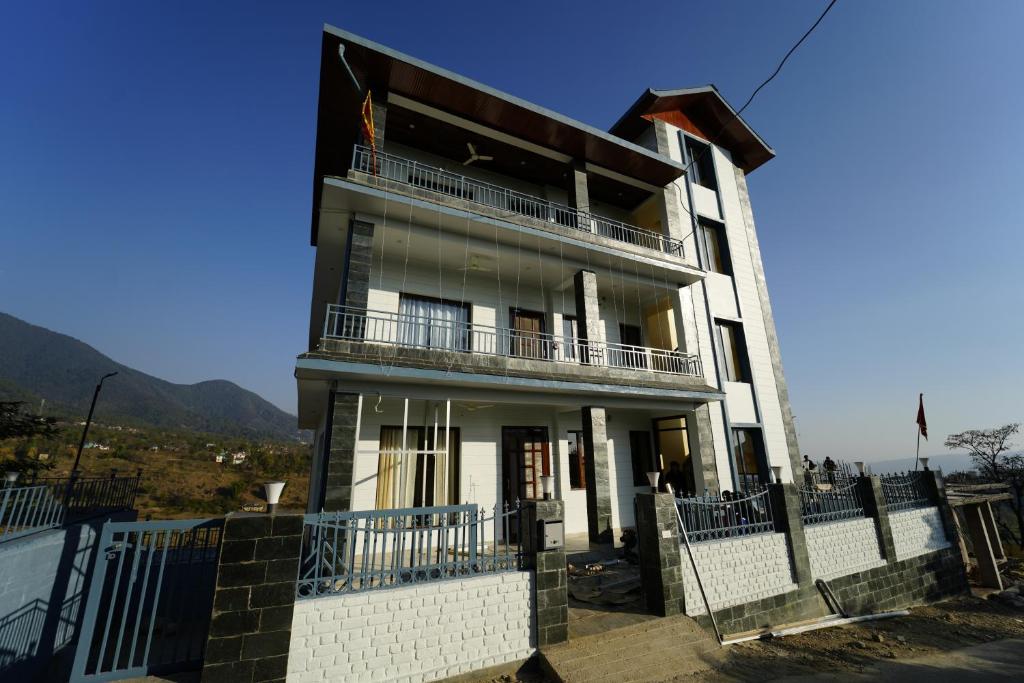 a tall white building with balconies and a fence at Prem BnB Palampur in Pālampur