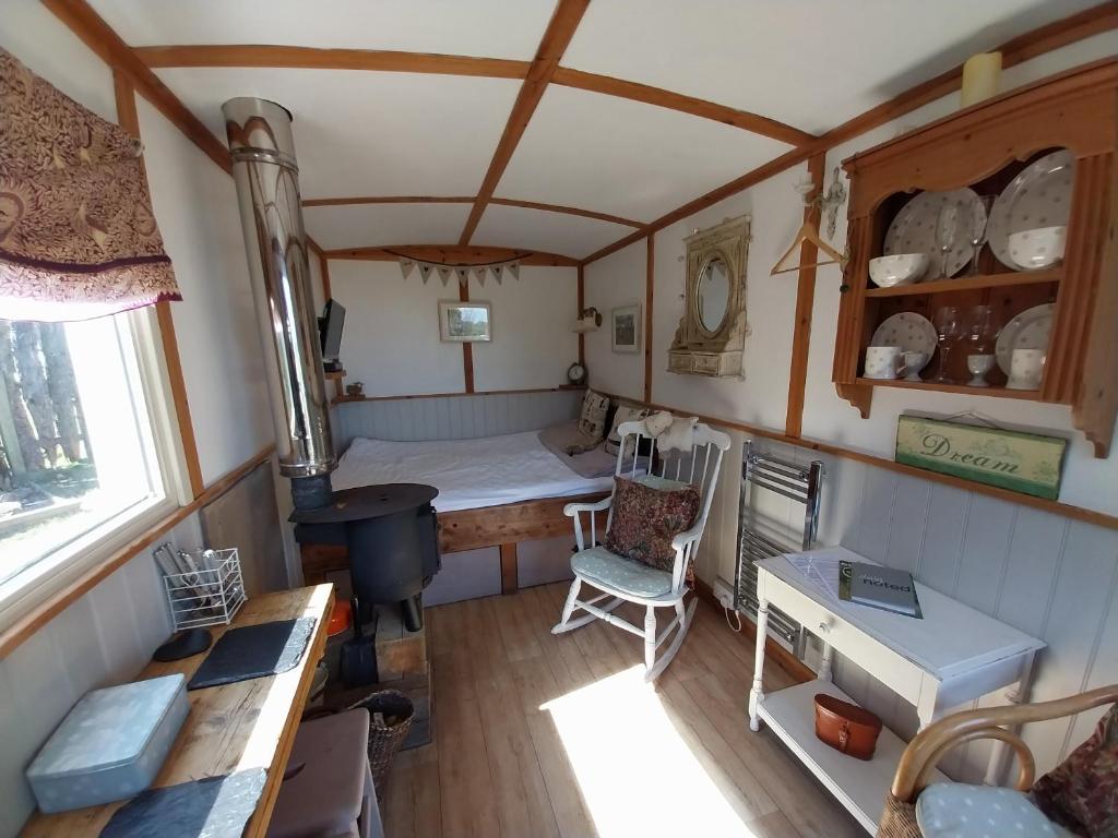 a small room with a bed and a stove at Meadowbeck - Shepherd Huts in Fylingdales