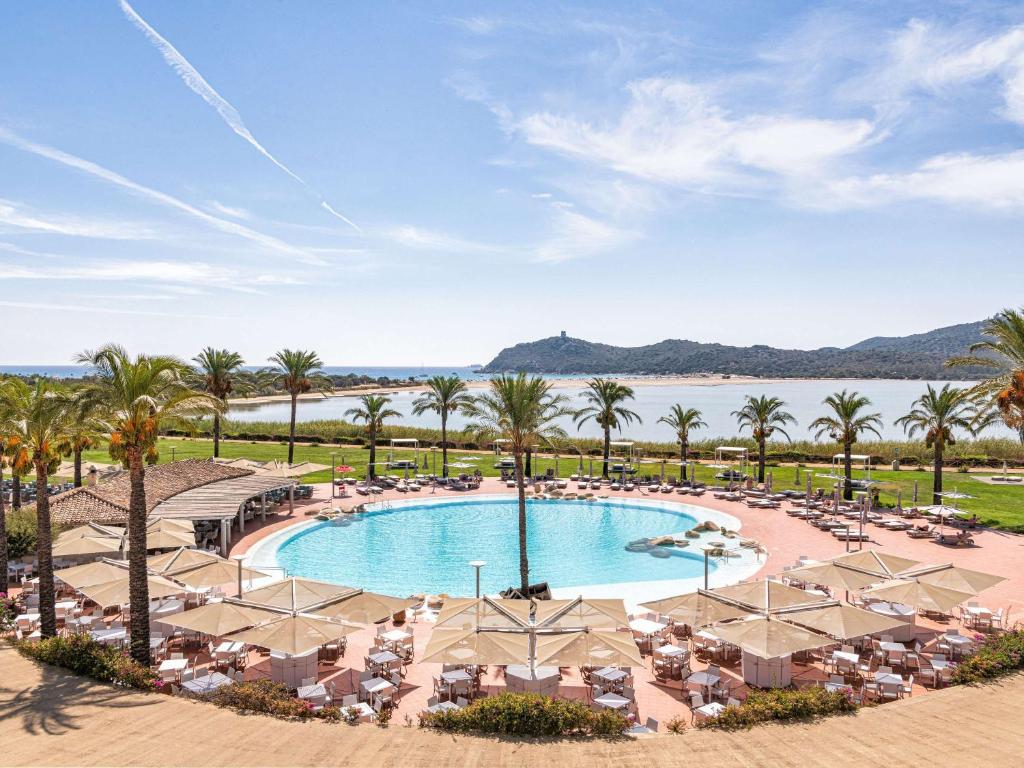 an aerial view of a resort pool with chairs and palm trees at Almar Timi Ama Resort & Spa in Villasimius
