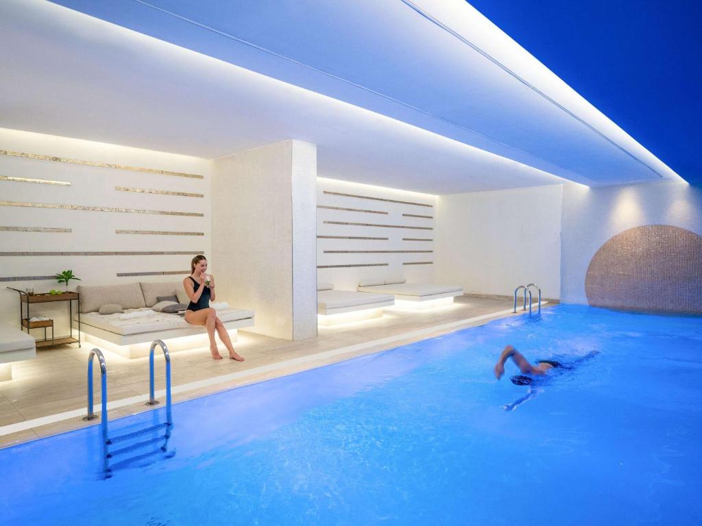 a woman sitting on a couch next to a swimming pool at Novotel Istanbul Bosphorus Hotel in Istanbul
