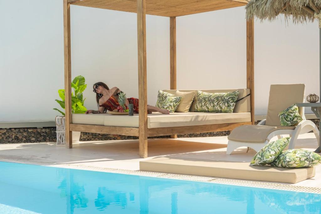 una mujer sentada en una cama junto a una piscina en Loukas & Emma Houses, en Perissa