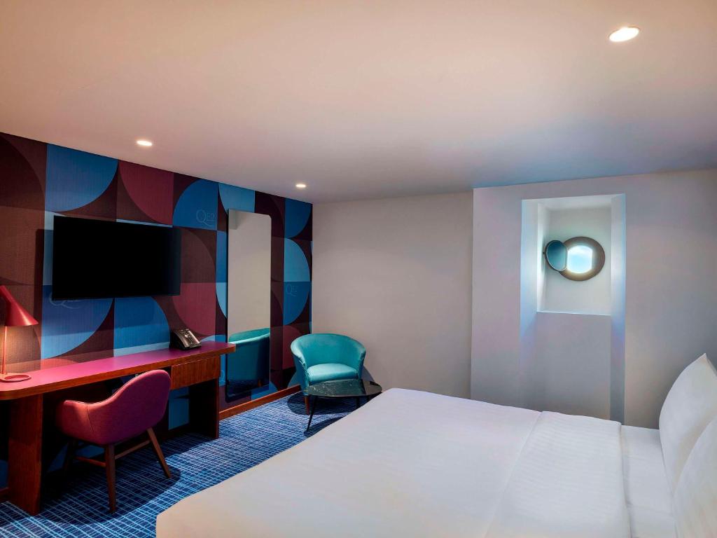 a hotel room with a bed and a desk and a tv at Queen Elizabeth 2 Hotel in Dubai
