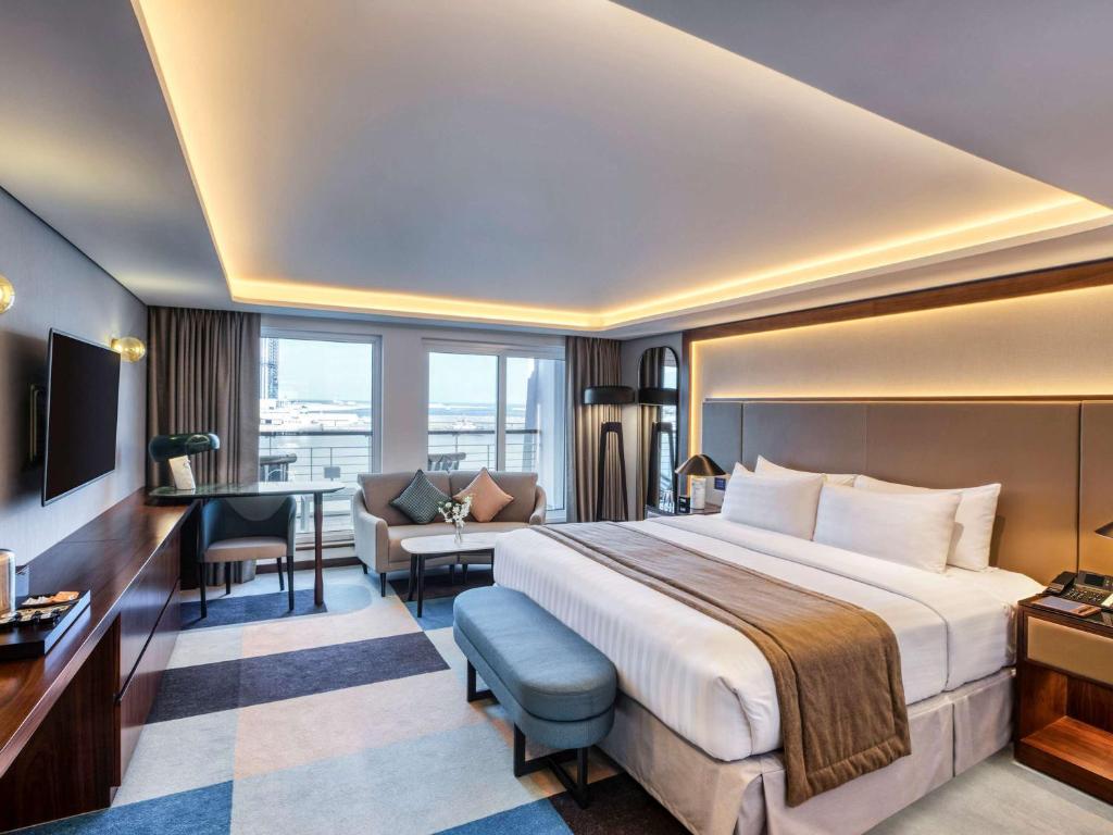 Queen Elizabeth 2 Hotel في دبي: غرفة الفندق بسرير كبير ومكتب