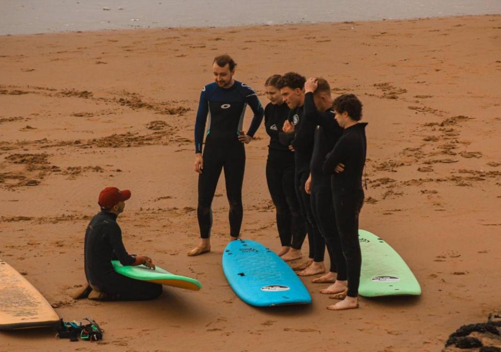 a group of people standing on a beach with surfboards at Sable beach surf camp taghazout in Taghazout