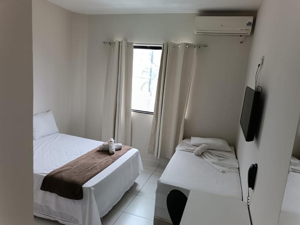 een slaapkamer met 2 bedden, een televisie en een raam bij POUSADA MEDITERRÂNEO in Lagarto