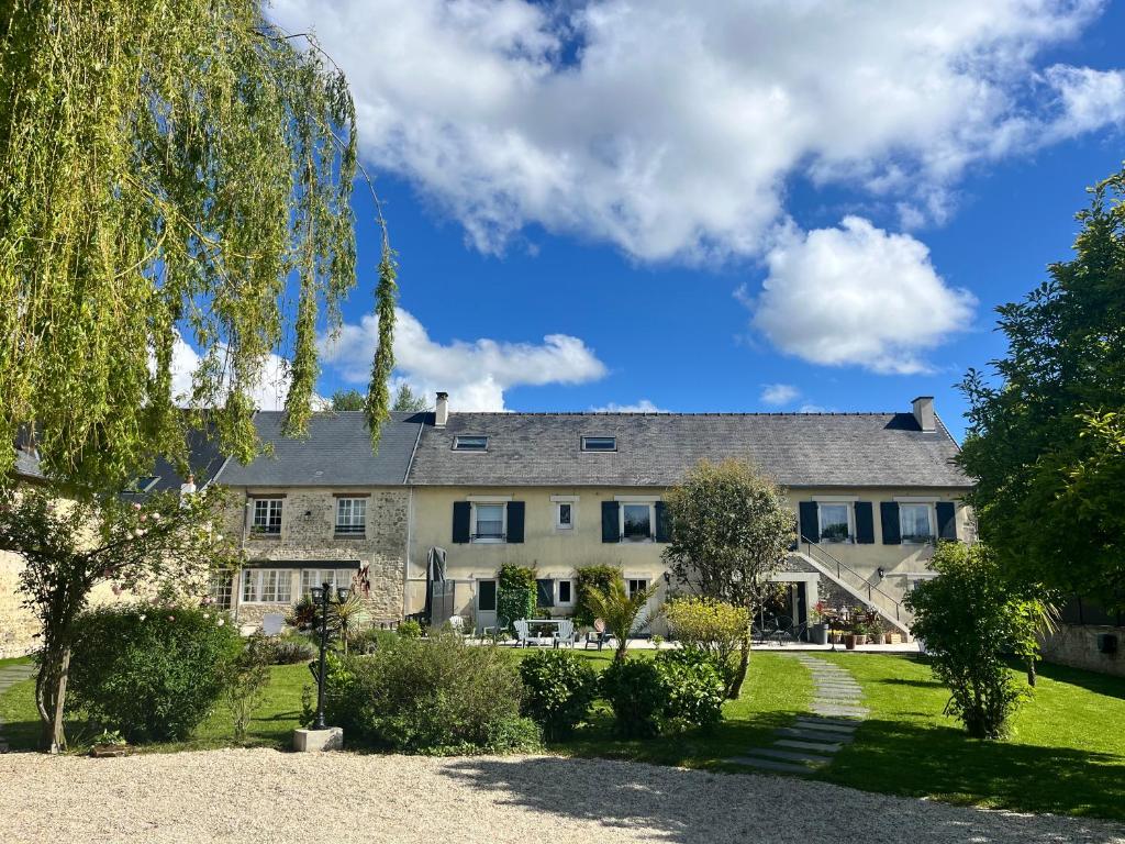 une grande maison avec un jardin en face de celle-ci dans l'établissement La Naomath - Maison d'hôtes, Hébergement insolite & Gîte, à Bayeux