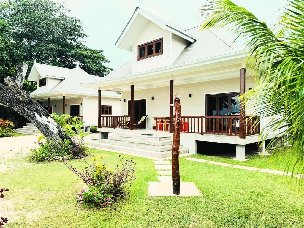 a white house with a porch and a yard at Digwa Beach Chalet in La Digue
