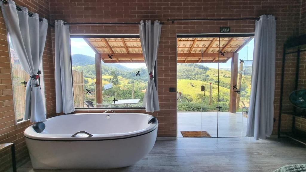 a bath tub in a bathroom with a large window at REFUGIO PIEMONTE Chalés in Socorro