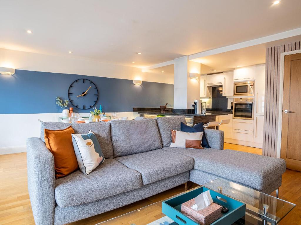 a living room with a couch and a clock on the wall at 2BR Harbor View near Babbacoombe Selfcheck-in by Belvilla in Torquay