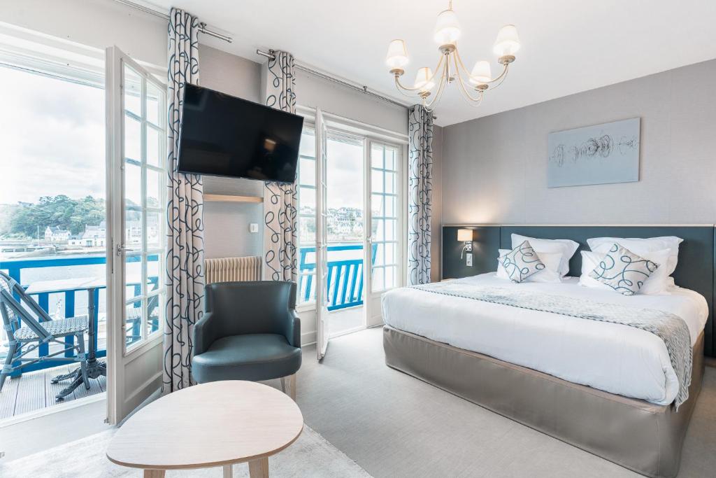 sypialnia z łóżkiem, telewizorem i krzesłem w obiekcie Logis hôtel restaurant Le Goyen w mieście Audierne