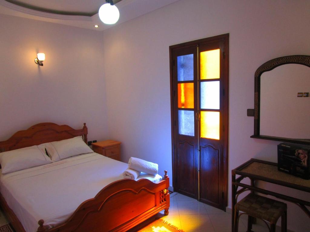 1 dormitorio con cama, espejo y ventana en Casa Mogador en Esauira