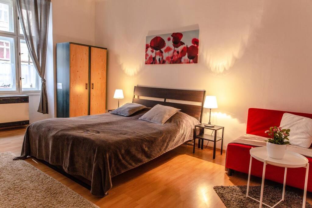 - une chambre avec un grand lit et une chaise rouge dans l'établissement Cozy Apartment in Prague's best area, à Prague