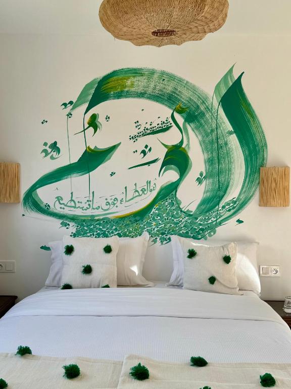 a bed with a painting of a wave at RIAD OASIS D'ASILAH in Asilah