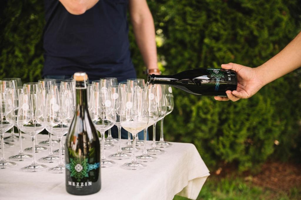 a person pouring a bottle of wine on a table with glasses at Casa Vatra Sinteului - Cu sala de evenimente de capacitate mare - Se inchiriaza integral in Socet