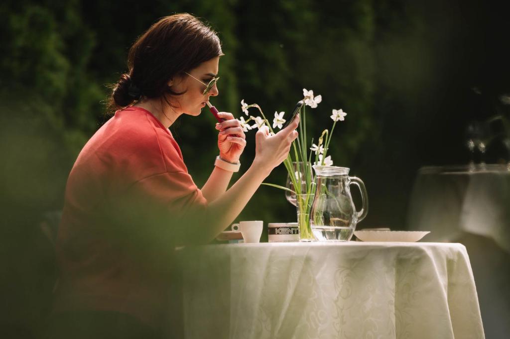 a woman sitting at a table looking at her cell phone at Casa Vatra Sinteului - Cu sala de evenimente de capacitate mare - Se inchiriaza integral in Socet