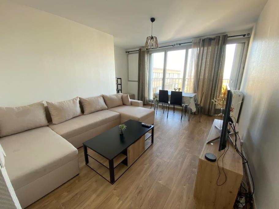 een woonkamer met een witte bank en een tafel bij Appartement - Nanterre in Nanterre