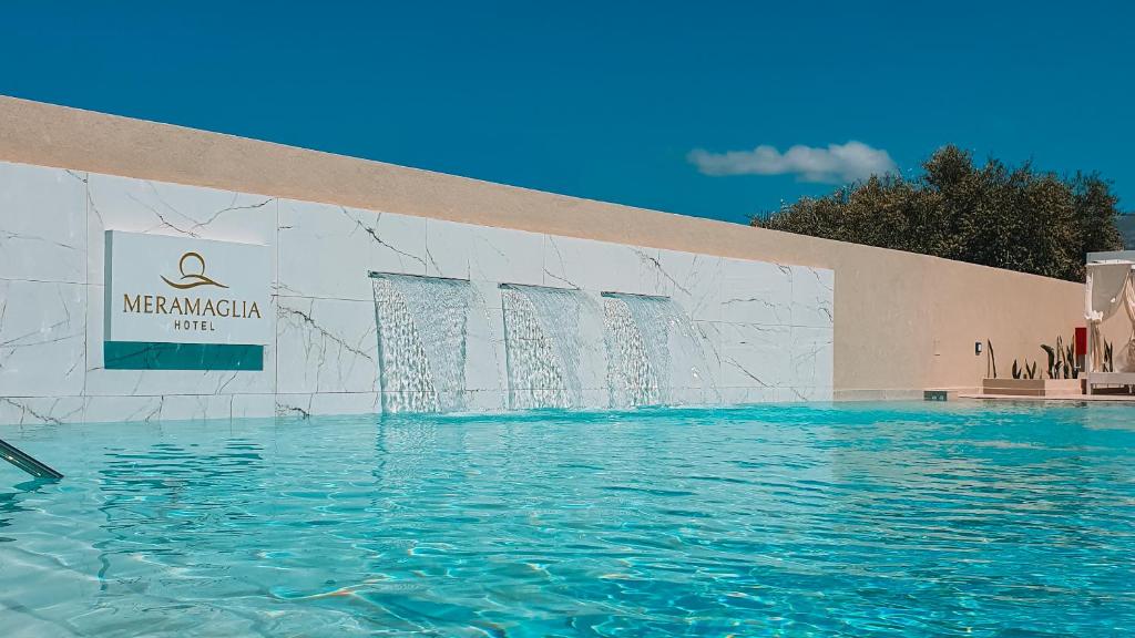 a swimming pool in front of a building with water at Meramaglia Hotel in Malia