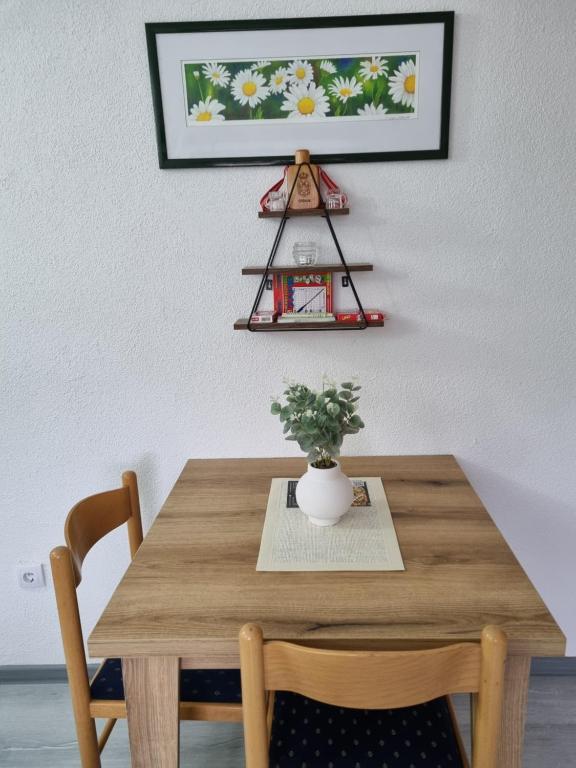 Apartmani Lale i Rada : طاولة خشبية عليها مزهرية ومصنع