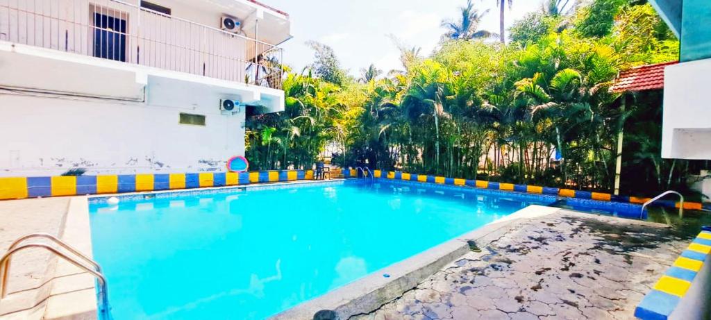 a large blue swimming pool next to a building at Coorg Dew Drops Resort in Kushālnagar