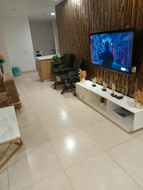 Luxury rooms studioLahore في لاهور: غرفة معيشة فيها تلفزيون كبير وكراسي